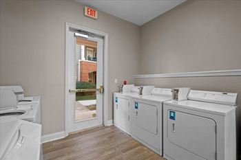 A room filled with washes and dryers in front of a door